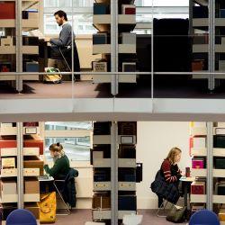 Three people studying in separate booths in a library